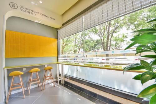 a bar with yellow stools and a large window at 7Days Inn Dali Erhai Park Branch in Dali
