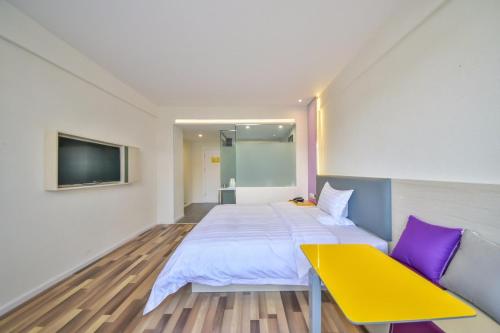 a bedroom with a bed and a yellow bench at 7Days Inn Dali Erhai Park Branch in Dali