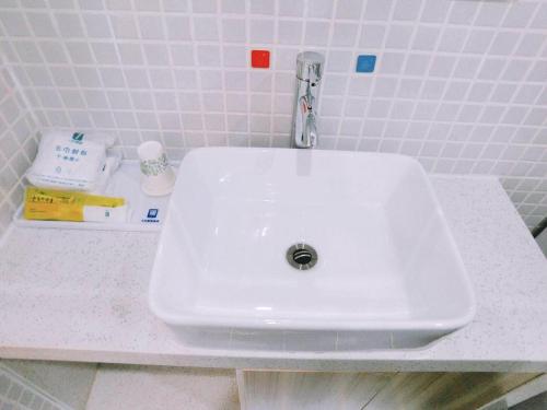 a white sink sitting on a counter in a bathroom at 7Days Inn Zhuhai Crocodile Island Bohuang Furniture Baiteng Lake Branch in Zhuhai