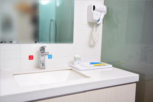 a bathroom with a sink and a phone on the wall at 7Days Inn Xuzhou Xincheng City Council Aoti Branch in Xuzhou