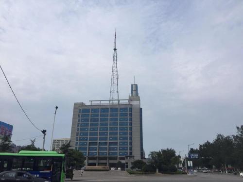 a tall building with a antenna on top of it at 7Days Inn Laiwu New Bus Station Branch in Laiwu