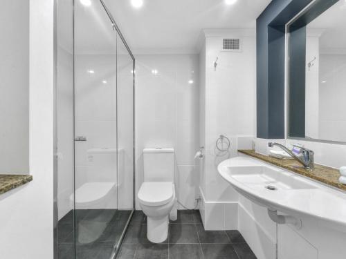 a bathroom with a toilet and a sink and a shower at Airport Heritage Motel in Brisbane