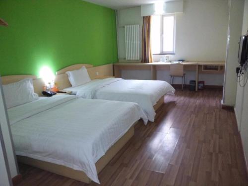 a hotel room with two beds and a green wall at 7Days Inn Tai'an Railway Station in Tai'an