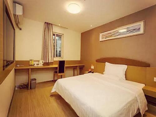 a bedroom with a bed and a desk with a computer at 7Days Inn Chengdu Yulin Province Stadium in Chengdu