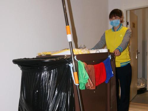 a woman wearing a mask standing next to a trash can at 7Days Inn Xianyang Xingping Jincheng Road Branch in Xianyang