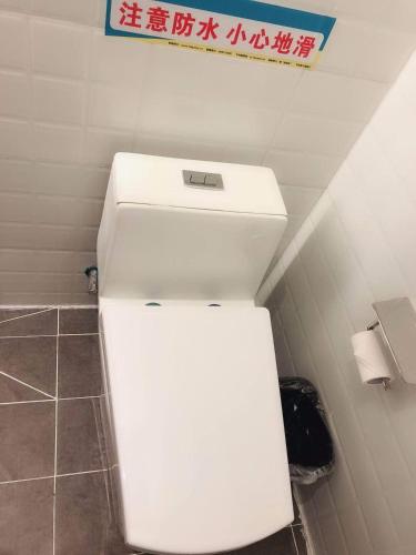 a white toilet in a bathroom with a sign above it at 7Days Inn Xianyang Xingping Jincheng Road Branch in Xianyang