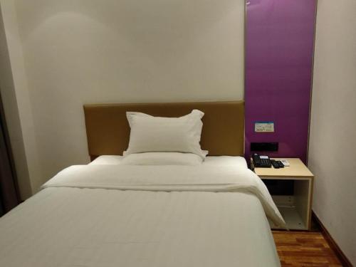 a white bed in a room with a side table at 7Days Inn Xianyang Xingping Jincheng Road Branch in Xianyang