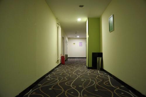 an empty hallway with green walls and a carpeted floor at 7Days Inn Changchun Hongqi Street University Town Nanhu Plaza Branch in Changchun