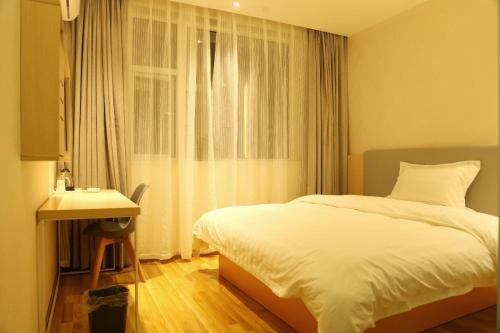 a bedroom with a bed and a desk and a window at 7Days Inn Neijiang Longchang Xinhua Street Branch in Neijiang