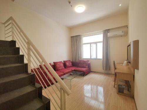 a living room with a red couch and a staircase at 7Days Inn Guiyang Wenchang Pavilion in Guiyang