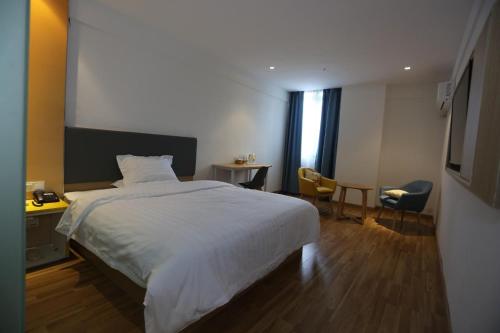 1 dormitorio con 1 cama blanca, mesa y sillas en 7 Days Inn Nanchang Qingshanhu Avenue Minfeng Road Branch, en Nanchang