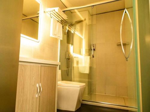La salle de bains est pourvue de toilettes et d'une douche en verre. dans l'établissement 7Days Inn Dongying Taihangshan Road Business Park Branch, à Dongying