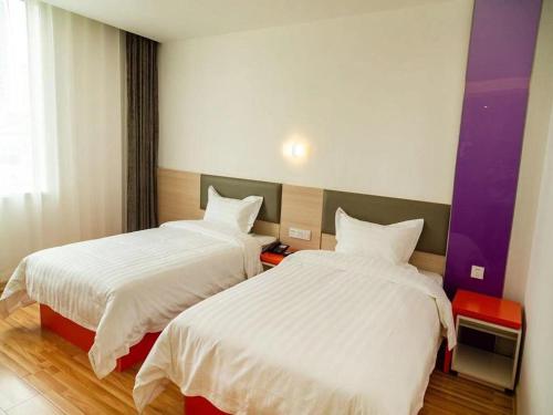 a hotel room with two beds with white sheets at 7Days Inn Dongying Taihangshan Road Business Park Branch in Dongying