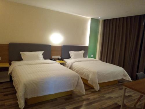 um quarto de hotel com duas camas com lençóis brancos em 7Days Inn Xiaoyi People's Hospital Branch em Yaopu