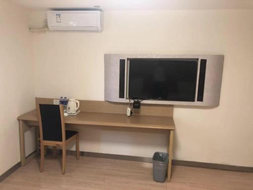 a desk with a television on a wall at 7 Days Hotel Shenyang Railway Station Zhongshan Square Branch in Shenyang