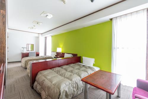 1 dormitorio con 2 camas y pared verde en Hotel S-Plus Hiroshima Peace Park en Hiroshima