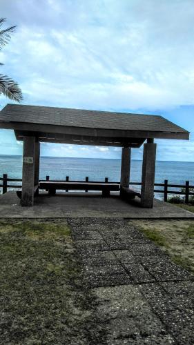a bench sitting on the beach with the ocean in the background at Chentien Changkuang Homestay in Changbin
