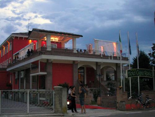 a red building with people standing outside of it at Hotel Cigno Reale in Rolo