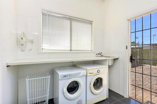 a laundry room with a washing machine and a window at Townhouse 3 in Broken Hill