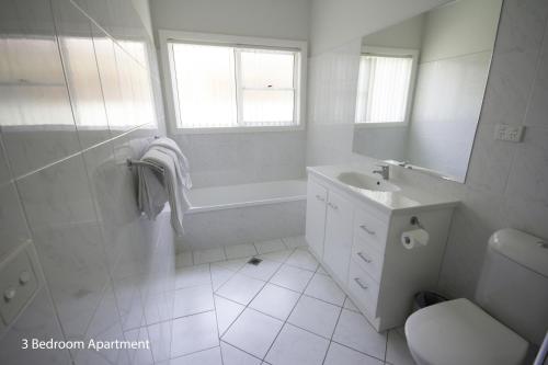 a white bathroom with a tub and a sink at The Charles in Wagga Wagga
