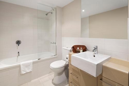 a white bathroom with a toilet and a sink at Quest Chermside in Brisbane