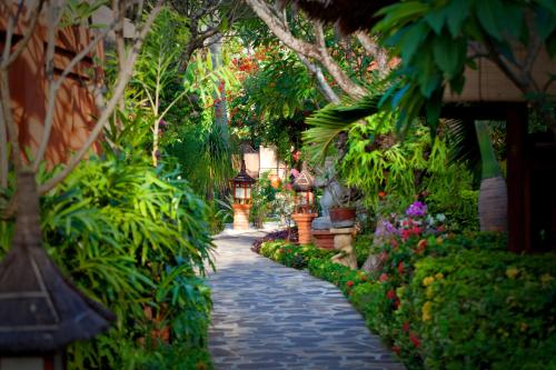 a stone path in a garden with flowers and plants at Puri Mas Boutique Resort & Spa in Senggigi 