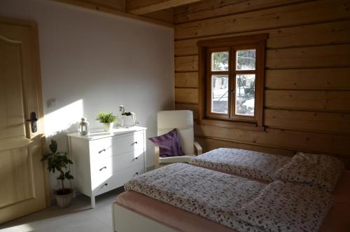 sypialnia z łóżkiem, komodą i oknem w obiekcie Apartmány u vlčích jam w mieście Petrowitz