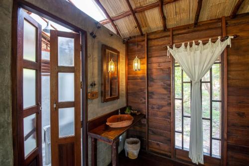a bathroom with a wooden wall with a sink and a window at The Moken Eco Village - SHA plus in Ko Phra Thong