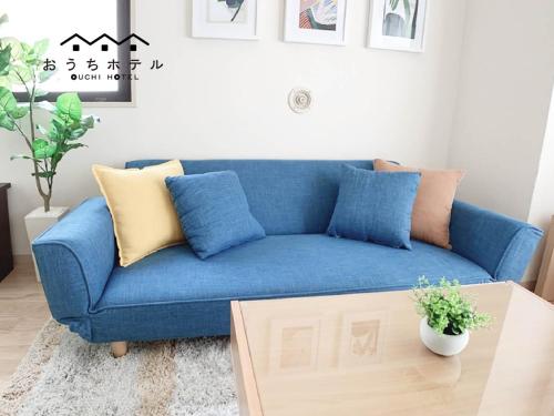 a blue couch in a living room with a table at OUCHI HOTEL Takaramachi in Hiroshima