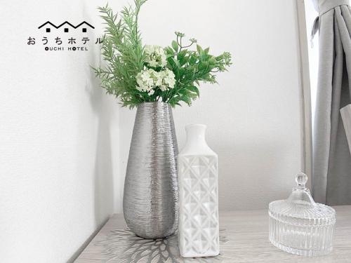 two vases sitting on a table with flowers in them at OUCHI HOTEL Takaramachi in Hiroshima