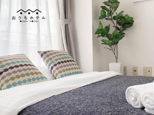 a bedroom with a bed with pillows and a window at OUCHI HOTEL Takaramachi in Hiroshima