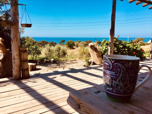 a coffee cup sitting on a wooden table with the beach at Beso Patara in Patara