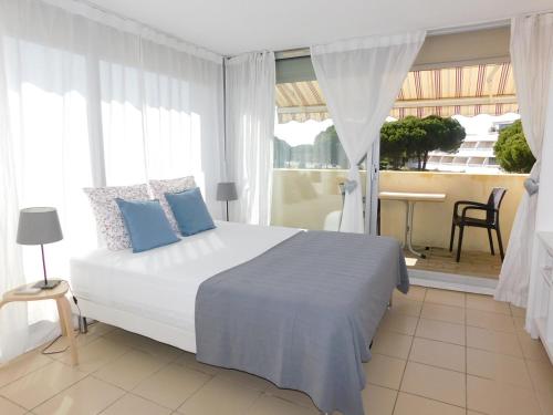 een slaapkamer met een groot wit bed met blauwe kussens bij studio 38 climatisé balcon vue mer in Le Grau-du-Roi
