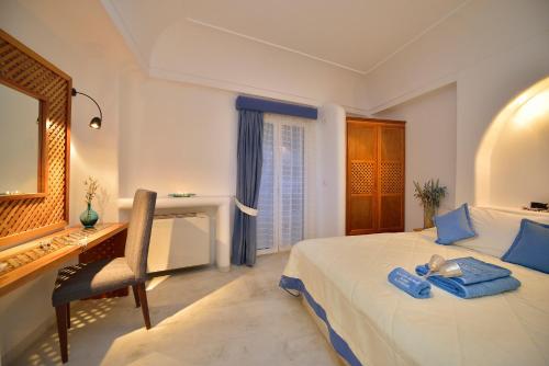 a bedroom with a bed and a desk and a mirror at Tamarix Del Mar Suites in Kamari