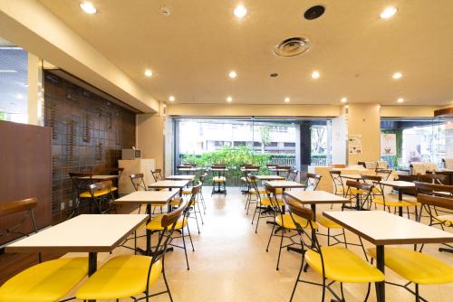 un restaurante vacío con mesas y sillas amarillas en Hotel Econo Kanazawa Station, en Kanazawa