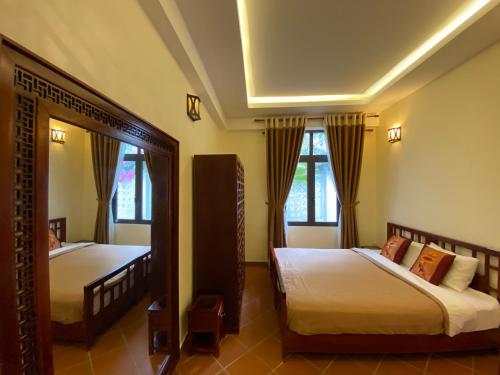 a bedroom with two beds and a mirror at Mekong Palm House in Can Tho