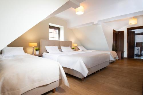 two beds in a room with white walls and wood floors at Piaskowy Brzeg in Jarosławiec