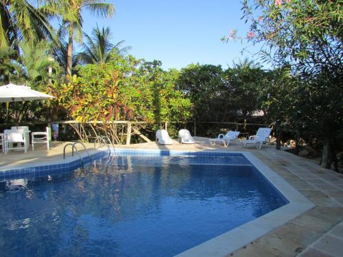 uma piscina com cadeiras, uma mesa e um guarda-sol em Pousada Ipitanga IV em Lauro de Freitas