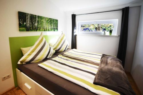 a bed with striped pillows and a window in a room at Apartment am Birkenfeld Allgäu Kaufbeuren in Steinholz