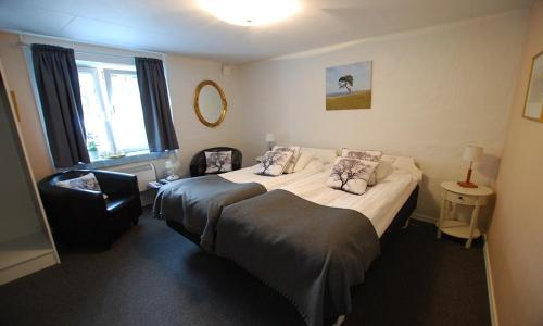a hotel room with two beds and a chair at Hotell Turistgården i Simrishamn in Simrishamn