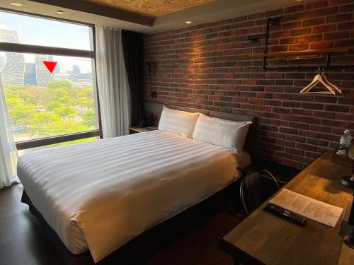 a bedroom with a large bed and a brick wall at City Suites - Kaohsiung Pier2 in Kaohsiung