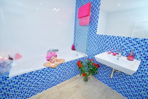 a woman sitting in a bath tub next to a sink at Ośrodek Wypoczynkowy Żagiel in Nakło