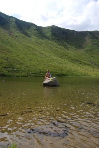 a person sitting on a rock in a body of water at Zelena Dacha in Dragobrat