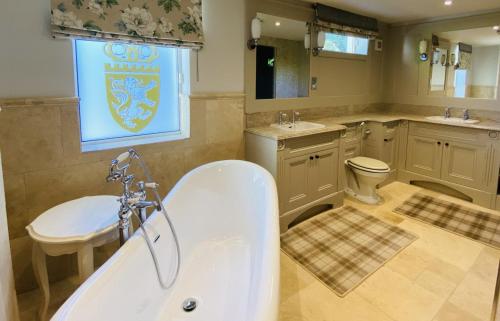 a bathroom with a tub and a toilet and a sink at Crossbasket Castle, Hotel & Restaurant in High Blantyre