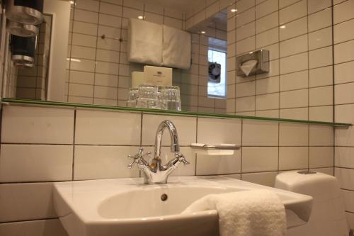 a bathroom with a sink and a mirror and a toilet at Skovshoved Hotel in Charlottenlund