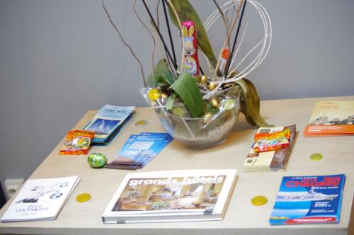 a table with books and a vase with a plant at Hôtel De Paris in Barneville-Carteret