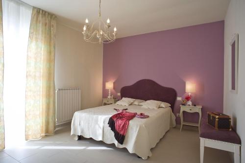 a bedroom with a bed with purple walls and a chandelier at Cevoli Country Resort in Lari