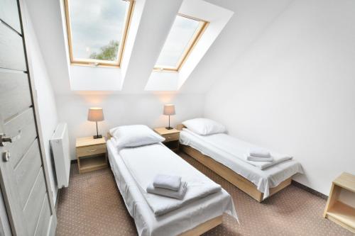 two beds in a small room with two windows at Pokoje 4you Szczecin in Szczecin