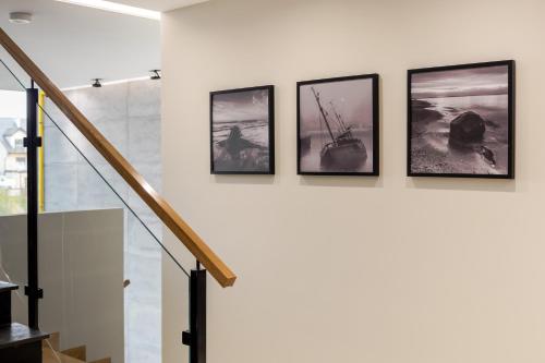 a group of framed photographs on a wall in a stair case at Apartamenty N7 in Darłówko