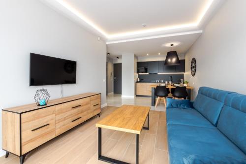a living room with a blue couch and a tv at Apartamenty N7 in Darłówko